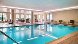 An indoor swimming pool with clear blue water, surrounded by lounge chairs and a table. - Courtyard by Marriott Tallahassee North/I-10 Capital Circle (Tallahassee)