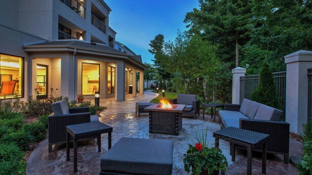 An outdoor patio area with a fire pit, seating, and a view of the building's interior. - Courtyard by Marriott Traverse City (Traverse City)