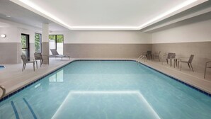 An indoor swimming pool with clear blue water, surrounded by lounge chairs and a tiled wall. - Courtyard by Marriott Traverse City (Traverse City)