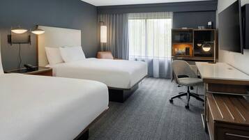 Une chambre d’hôtel avec deux lits, un bureau, une chaise, une télévision et un mini-bar.