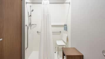 A bathroom with a shower, a toilet, and a small wooden table.