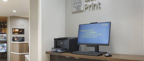 A reception desk with a computer, a printer, and a sign that reads "Quick Print".