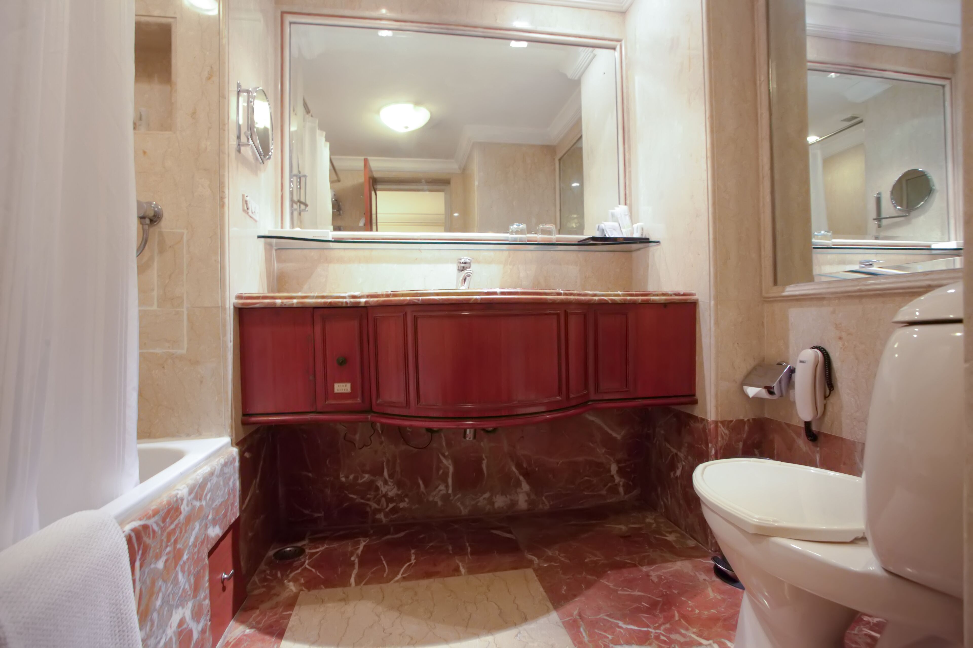 Een badkamer met een marmeren vloer, een glazen wastafel en een wit toilet.