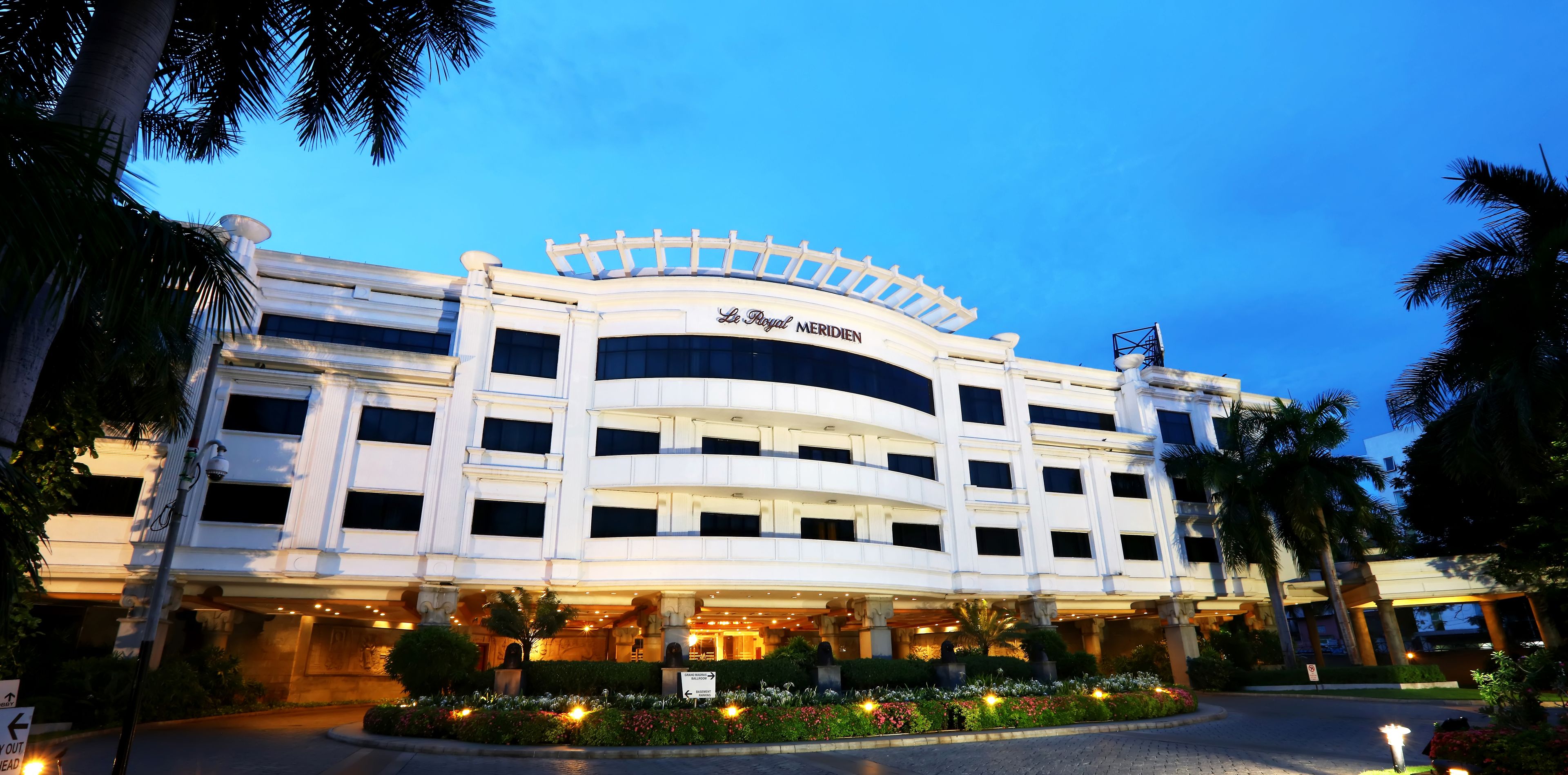 A multi-story hotel with a classic architectural design, featuring a prominent marquee sign at the top and a well-lit entrance.