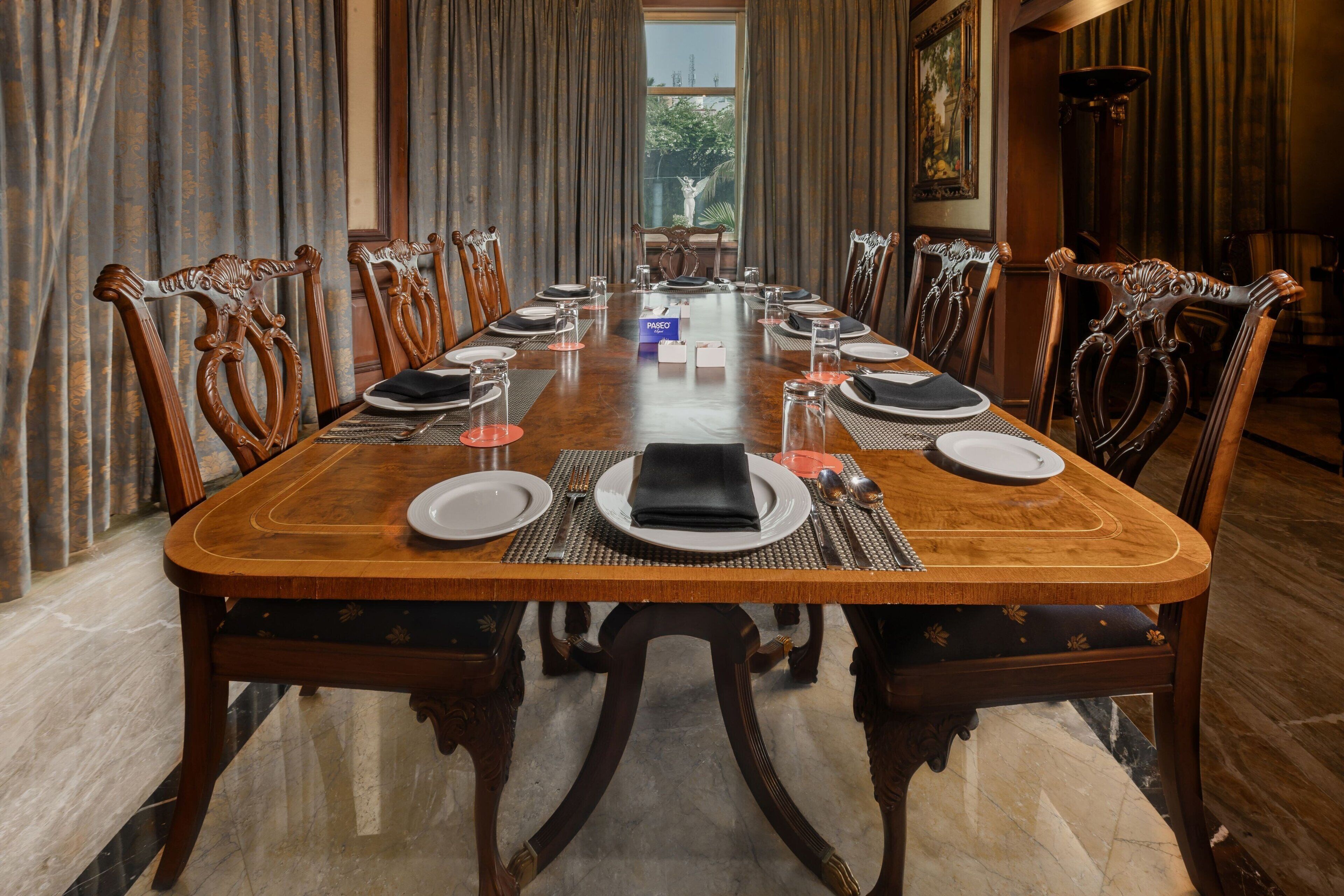 Een statig eetzaal met een lange houten tafel gedekt voor een maaltijd, omringd door decoratieve stoelen.