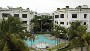Un hotel moderno con piscina central rodeada de palmeras y follaje.