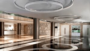 Un vestíbulo amplio con un piso de mármol pulido, candelabros modernos y una zona de recepción.