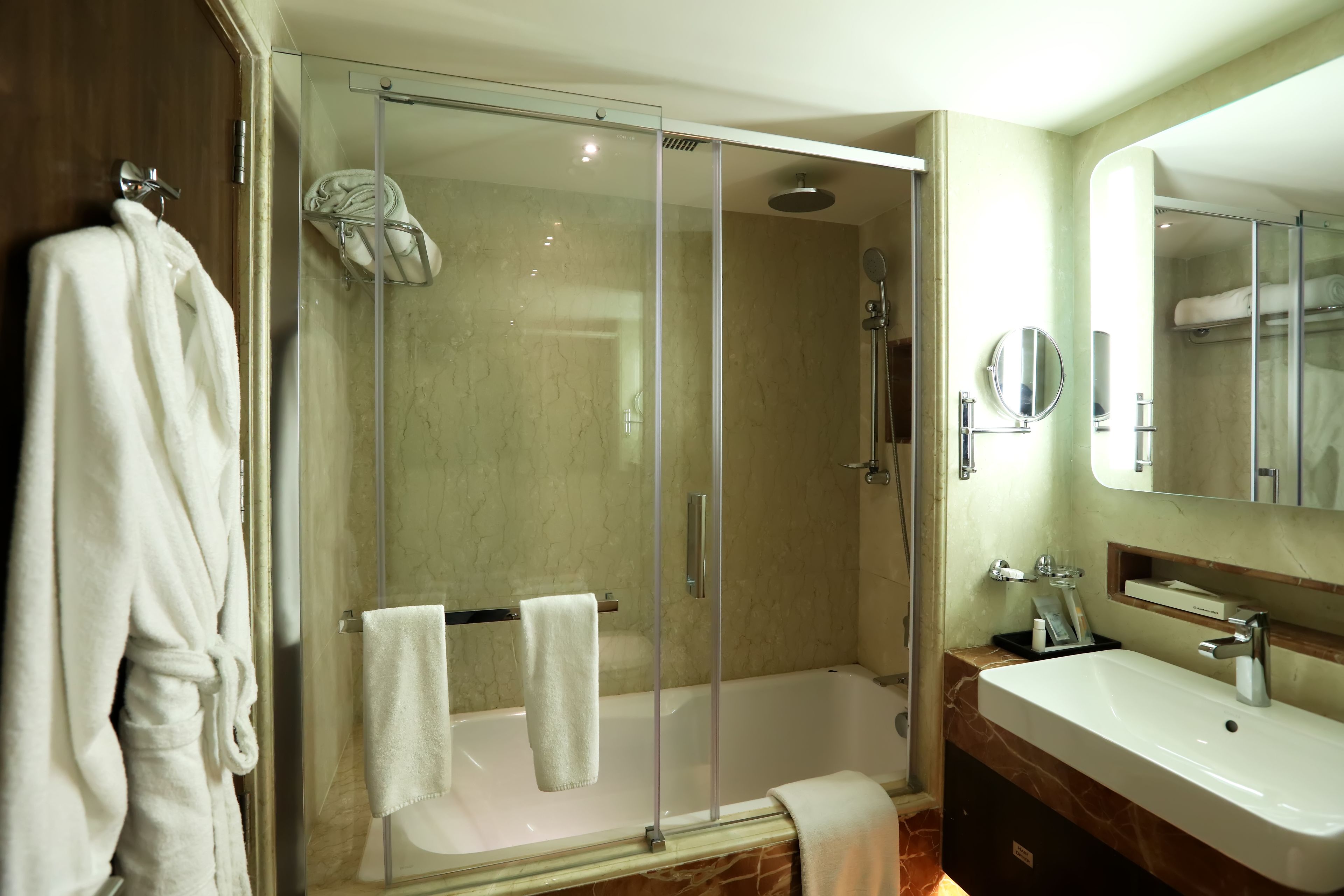 Un baño moderno con ducha envuelta en vidrio, bañera y tocador con espejo.