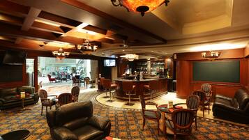 Um saguão de hotel com sofás de couro, uma área de bar e um tapete estampado.