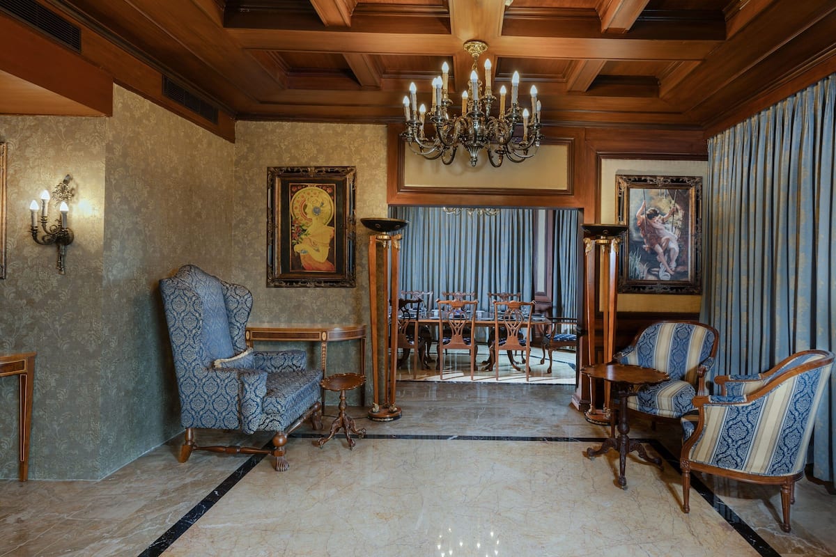 Una sala elegante con candelabro, sillas estampadas, una mesa de comedor y obras de arte enmarcadas.