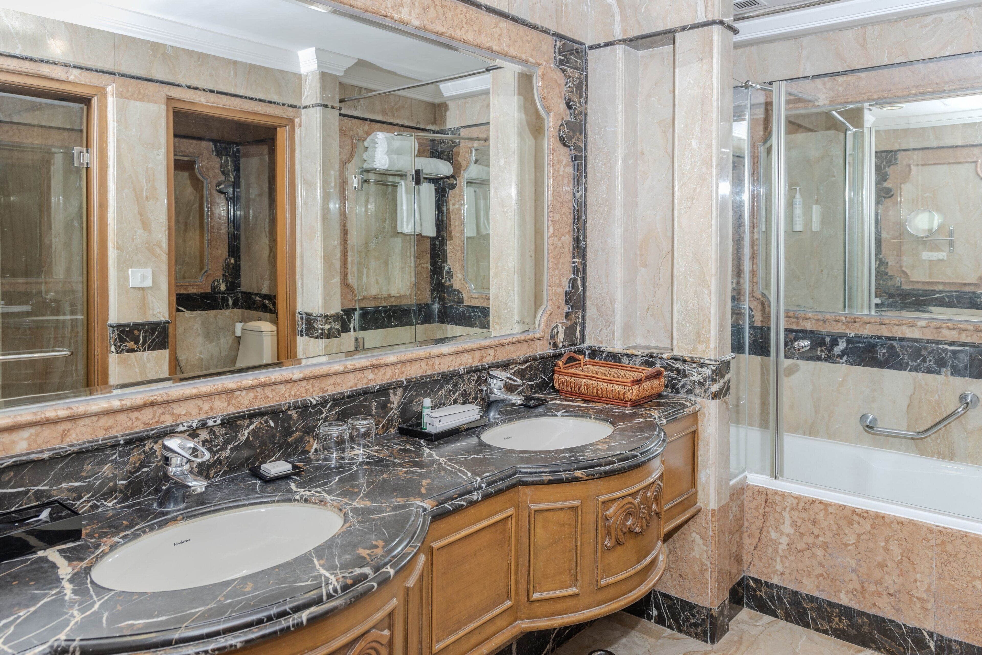 A bathroom with two sinks, a large mirror, and a shower area.