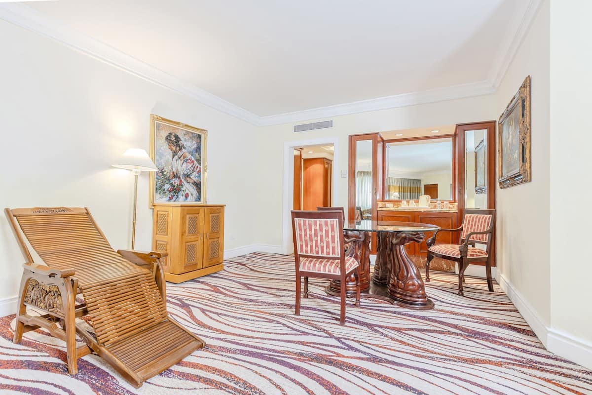 Una habitación con una silla de madera, una mesa de comedor con sillas, un armario y un cuadro en la pared.