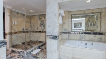 A luxurious bathroom with a glass-enclosed shower, a large bathtub, and marble flooring.