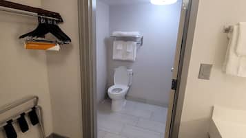 A bathroom with a toilet, a towel rack, and a shower area.