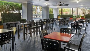 Un espace de restauration en plein air doté de plusieurs tables et chaises, de ventilateurs de plafond et offrant une vue sur la verdure environnante.
