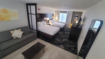 A hotel room with a sofa, a bed, a desk, and a mirror.