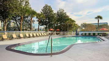 Una piscina al aire libre, sombrillas, sillones reclinables de piscina