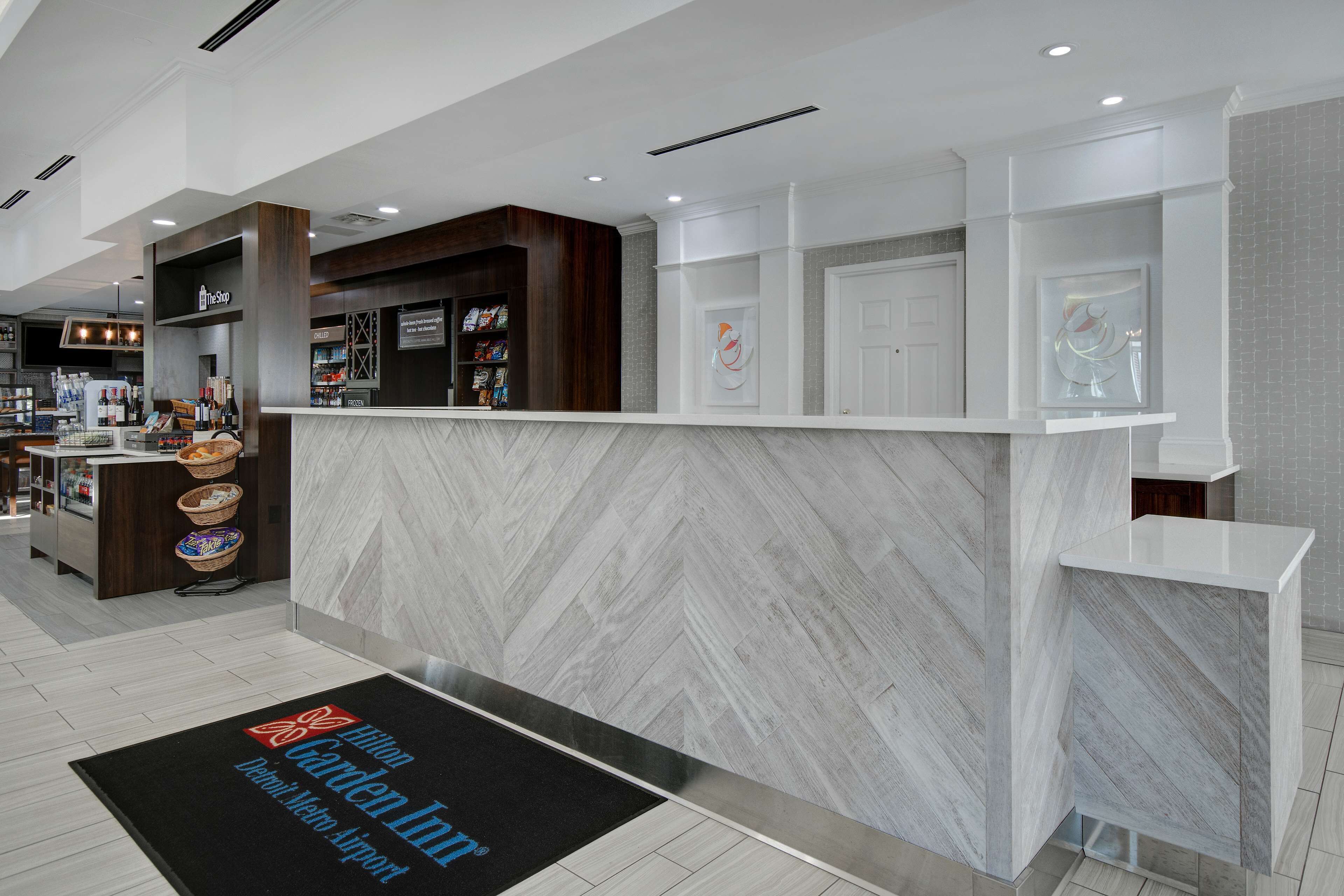 A modern reception area with a marble counter, a small kiosk, and a reception desk.