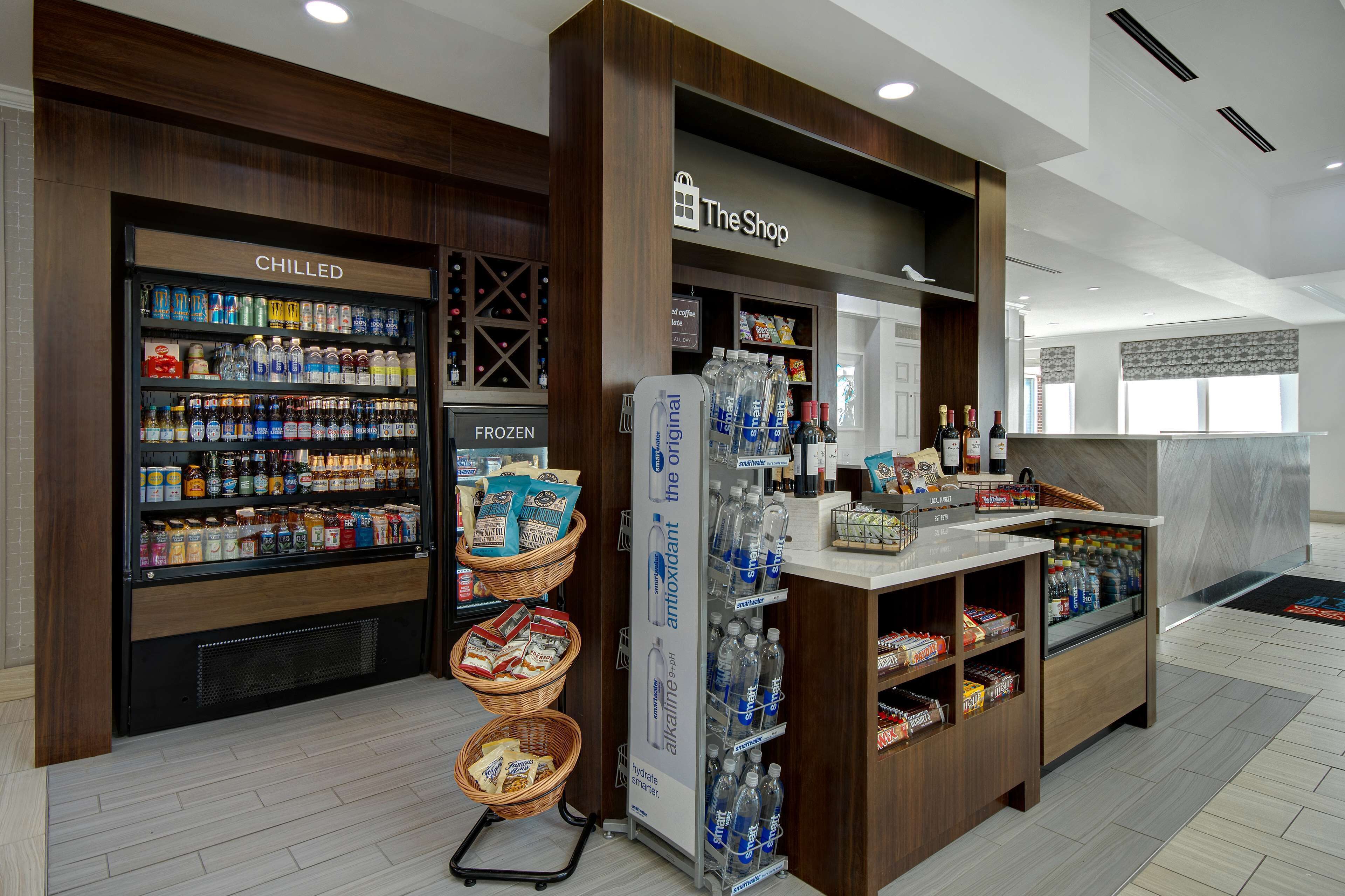 Una tienda con secciones de productos refrigerados y congelados, un punto de hidratación y una zona de venta.