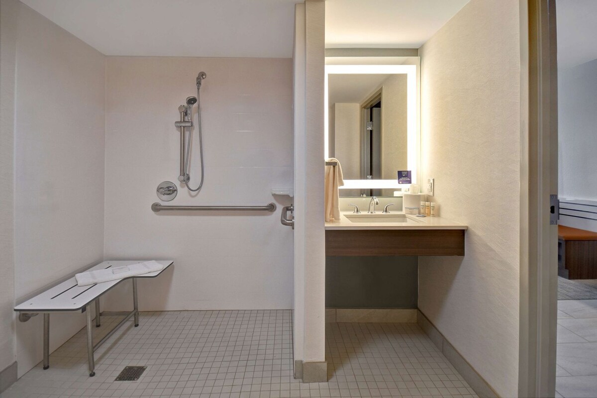 A bathroom with a shower, a sink, and a mirror.