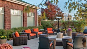 An outdoor patio area with wicker furniture, including sofas and chairs, and a round table.