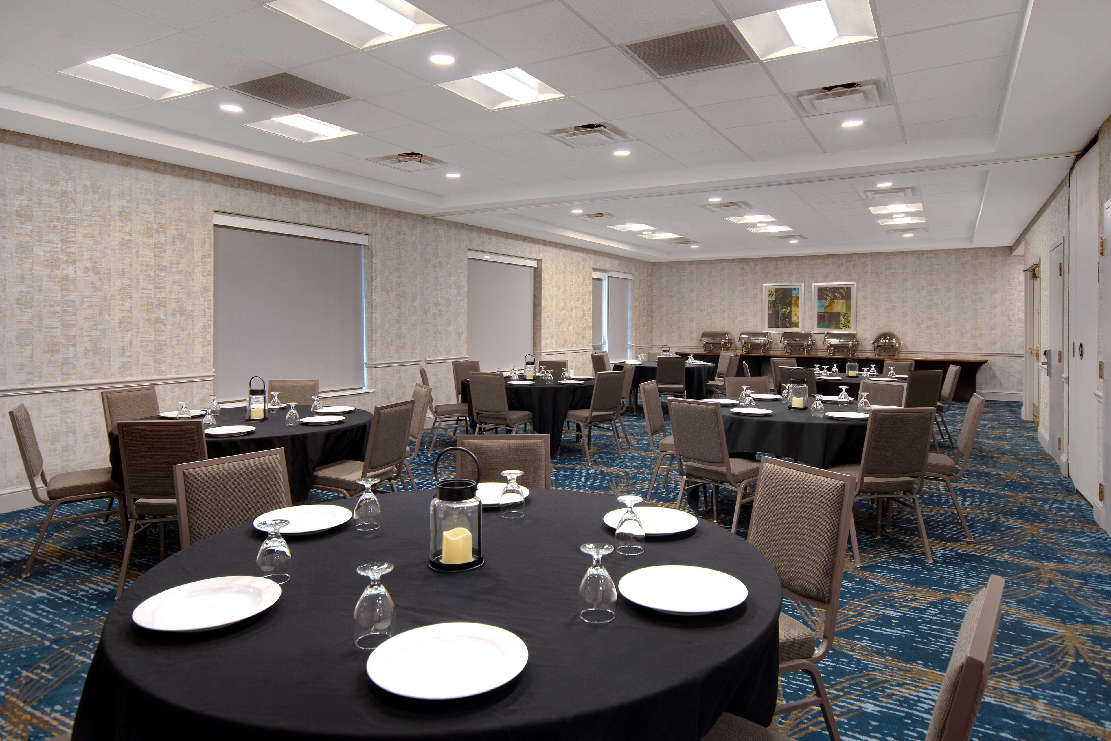 A conference room with multiple tables, chairs, and a carpeted floor.