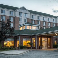 A multi-story hotel with a brick facade, large windows, and a covered entrance.