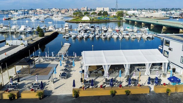 A marina with boats, a white tented area, and a bridge in the background. - Seaport Resort & Marina (Fairhaven)