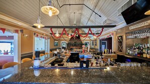 A bar area with a granite countertop, bar stools, and a television mounted on the wall. - Seaport Resort & Marina (Fairhaven)
