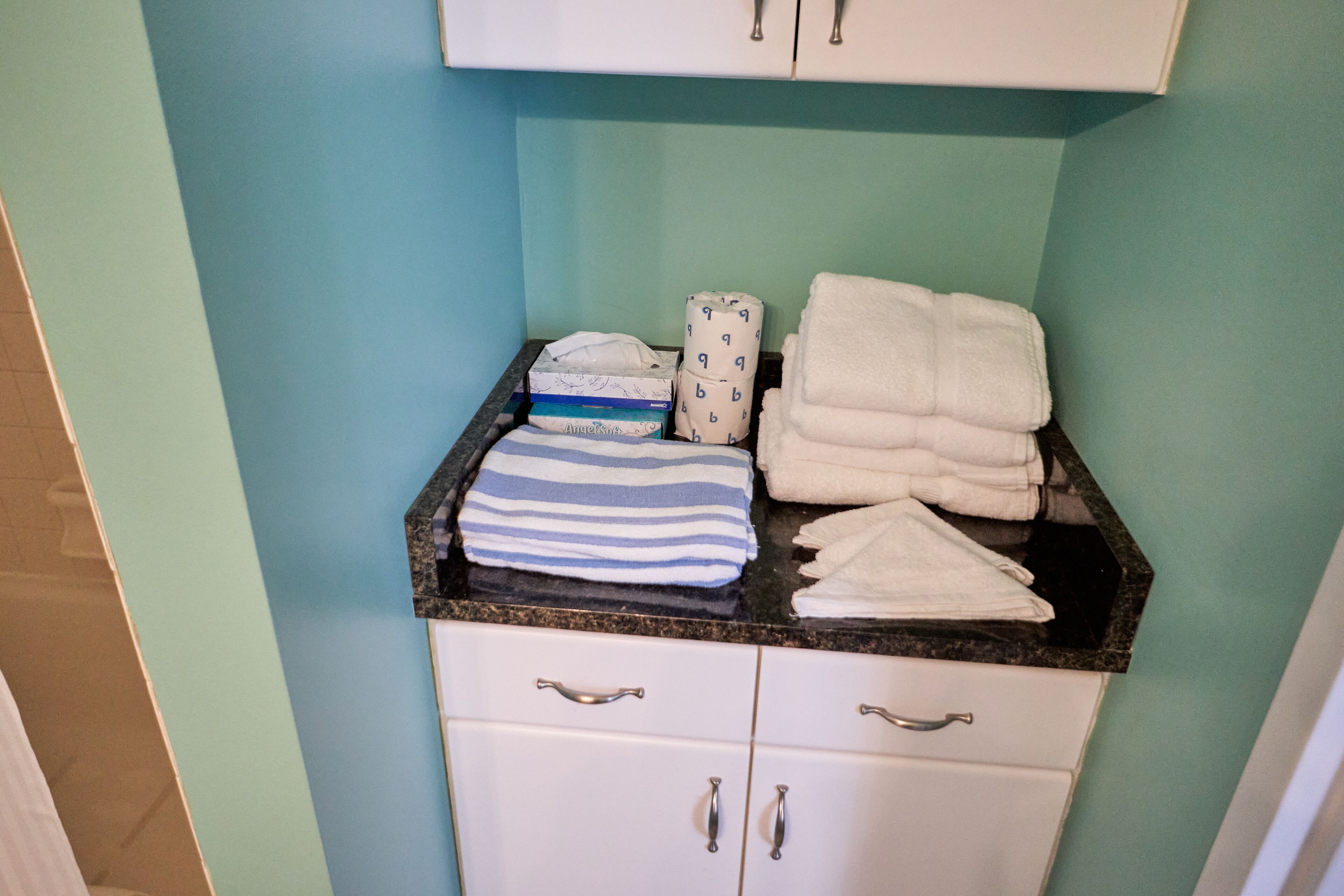 A bathroom with a countertop holding towels and a baby changing station.