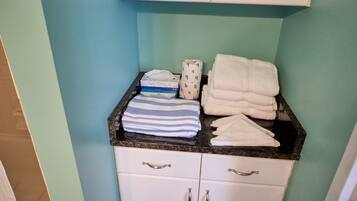 A bathroom with a countertop holding towels and a baby changing station.