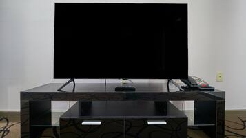 Een zwarte entertainmentkast met een flatscreen televisie, een telefoon en een afstandsbediening.