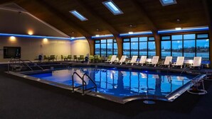 An indoor swimming pool with clear views of the outside, surrounded by lounge chairs and tables. - Seaport Resort & Marina (Fairhaven)
