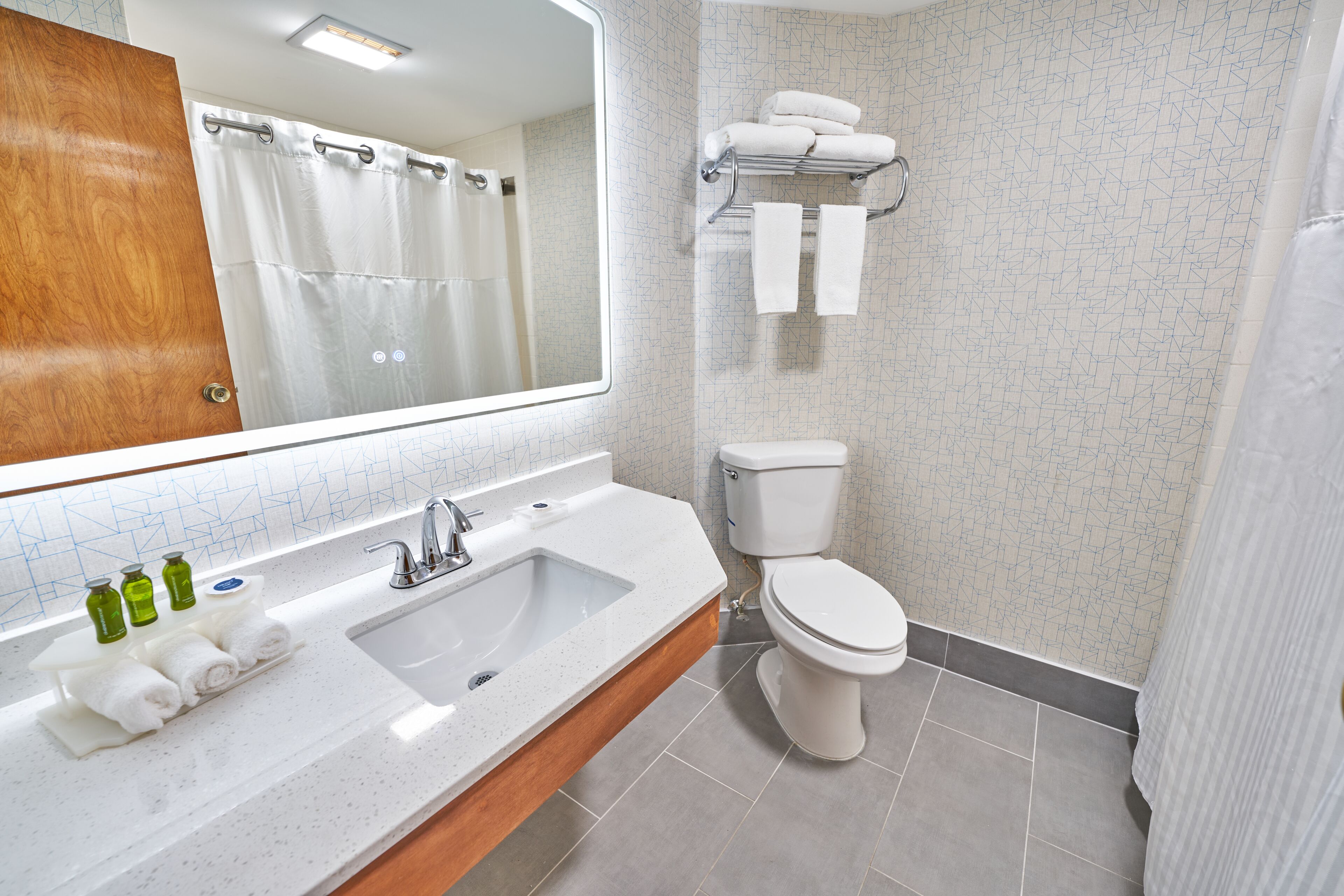 A bathroom with a sink, mirror, toilet, and towel rack.
