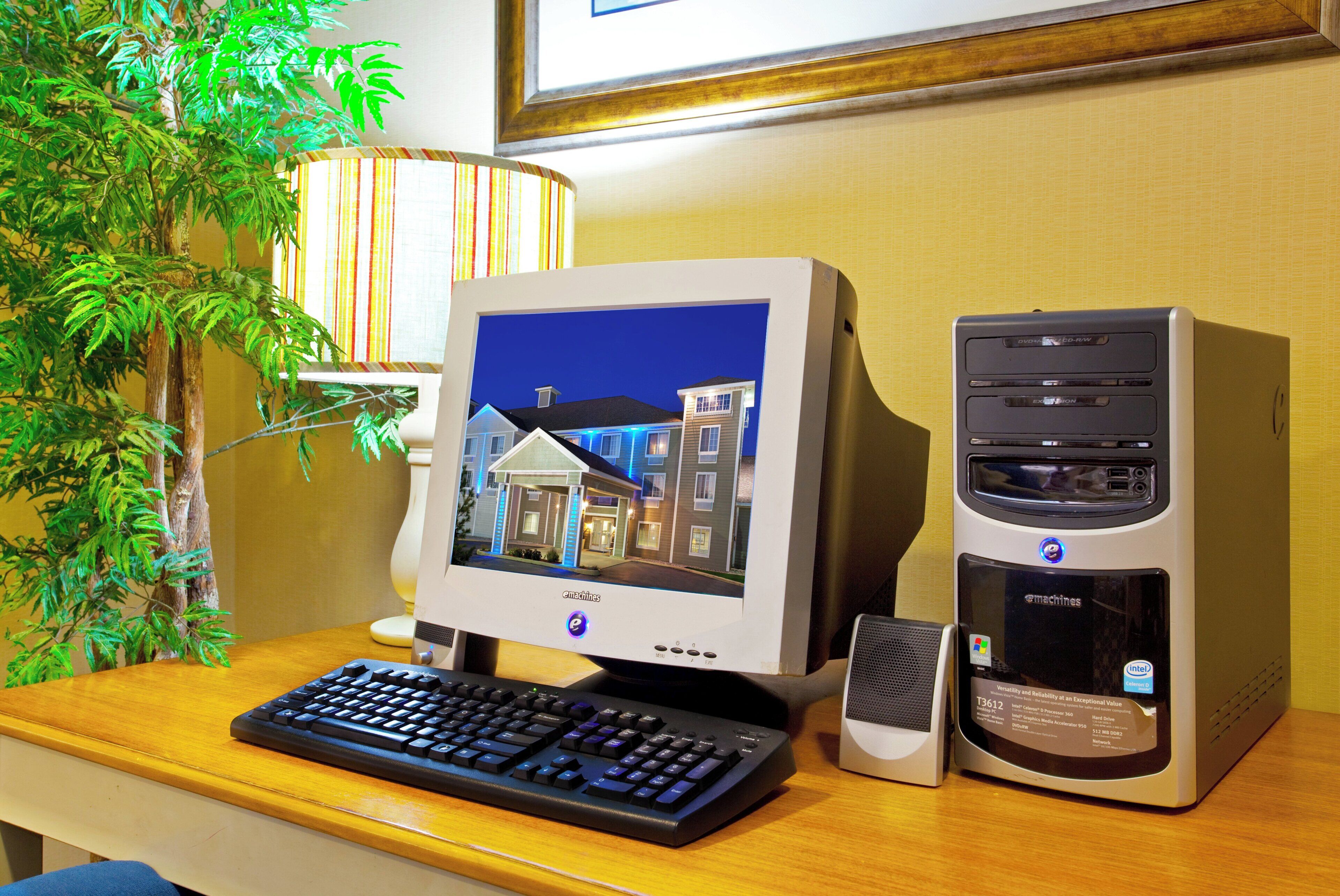 A desktop computer setup with a monitor, keyboard, and tower on a wooden desk.
