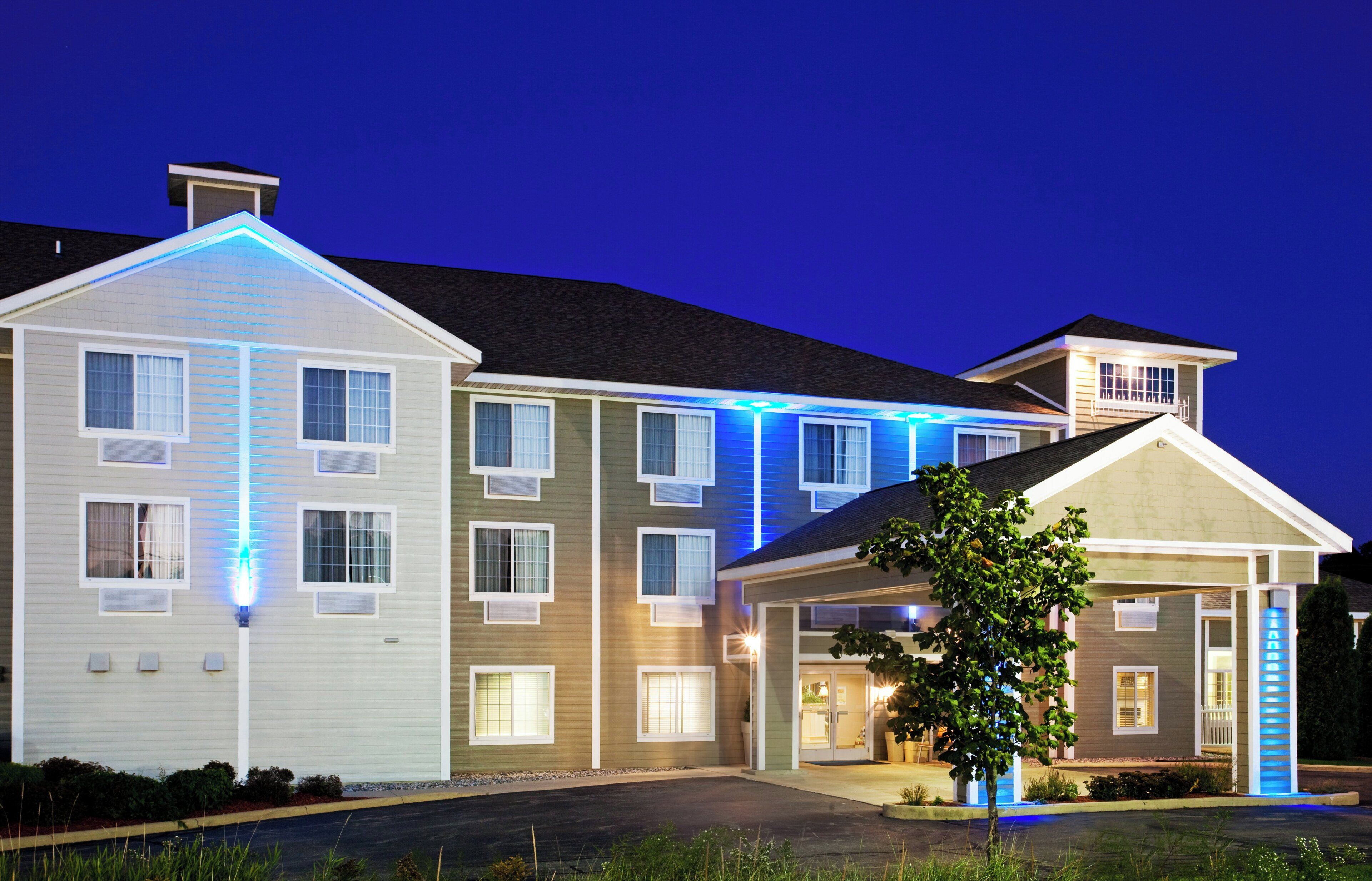 A multi-story residential building with a covered entrance and a tree in the foreground.