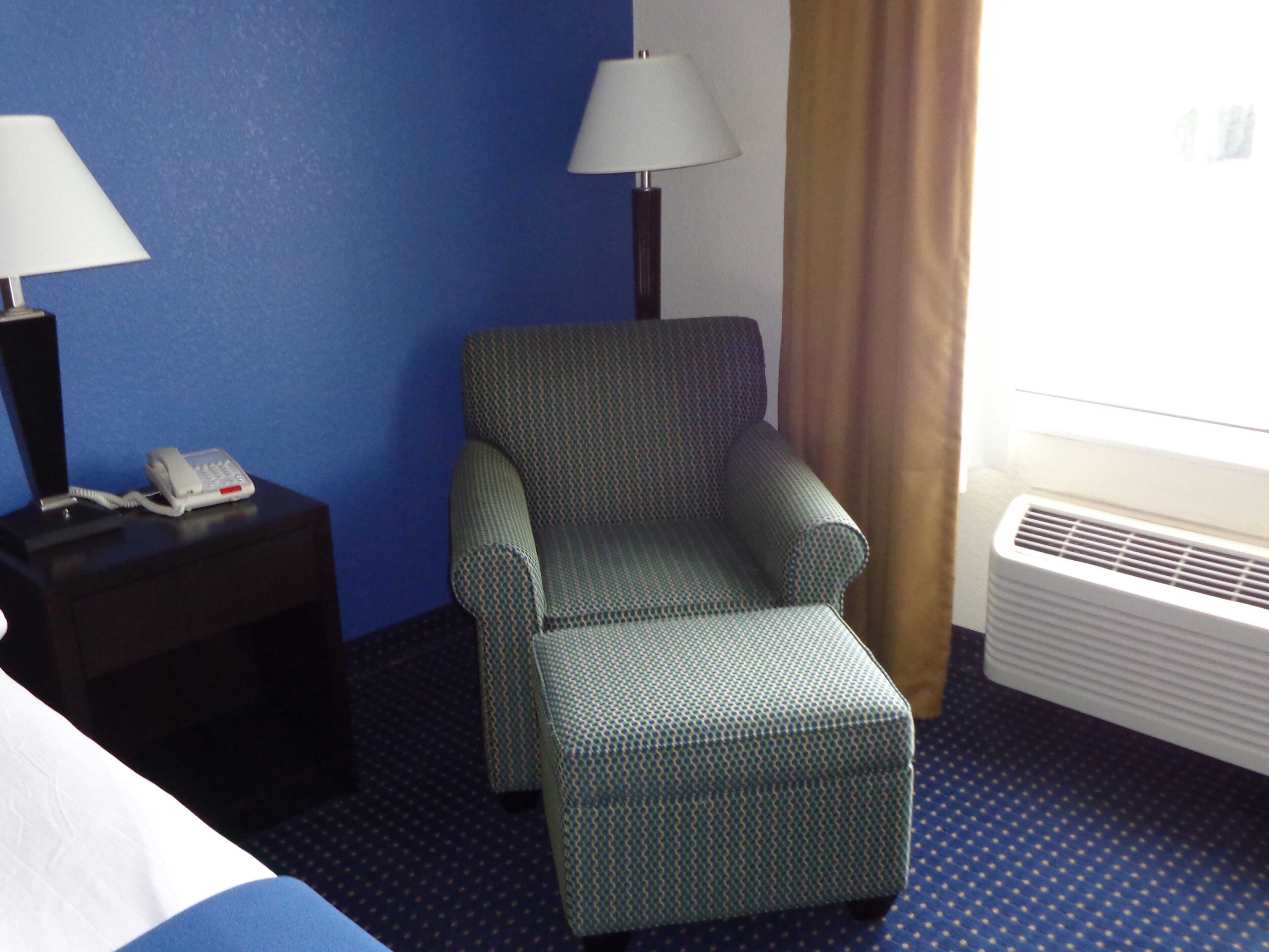 Une chambre d’hôtel équipée d’un lit, d’une chaise, d’une lampe, d’un téléphone et d’un appareil de climatisation.