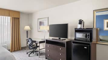 A hotel room with a bed, a desk with a chair, a television, a microwave, and a coffee maker.
