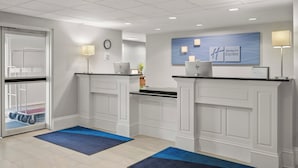 Uma área de recepção com um relógio, a placa Holiday Inn Express e um balcão de atendimento.