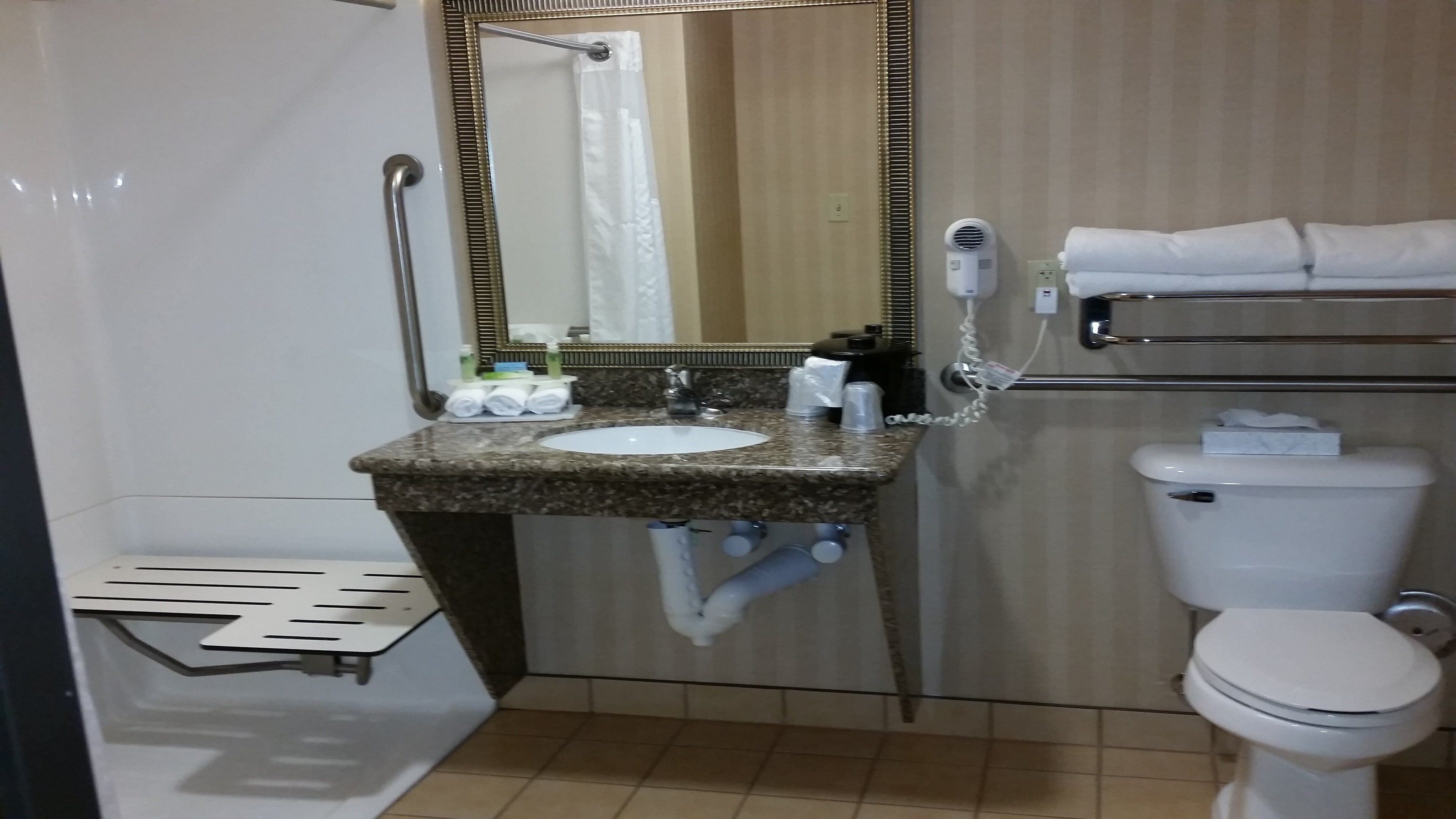Une salle de bain équipée d’un lavabo, d’un miroir, de toilettes et d’un porte-serviettes.