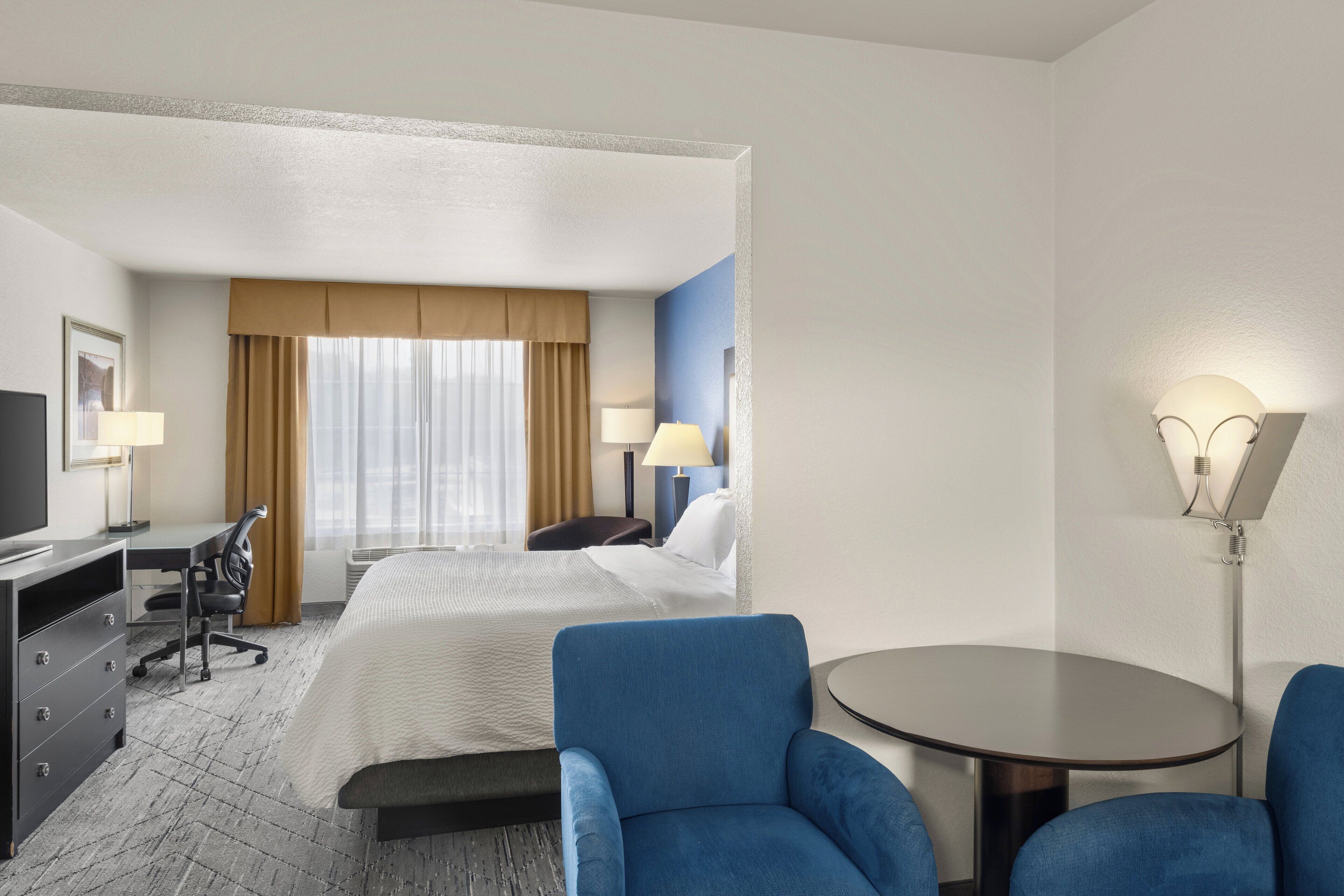 Une chambre d’hôtel équipée d’un lit, d’un bureau, de chaises et d’un téléviseur.