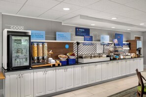 Un buffet de petit-déjeuner proposant une variété d’aliments, notamment des yaourts, du lait et des plats chauds.