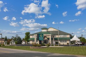 A hotel with a green roof and a sign for 'Quality Inn & Suites by Choice Hotels'.
