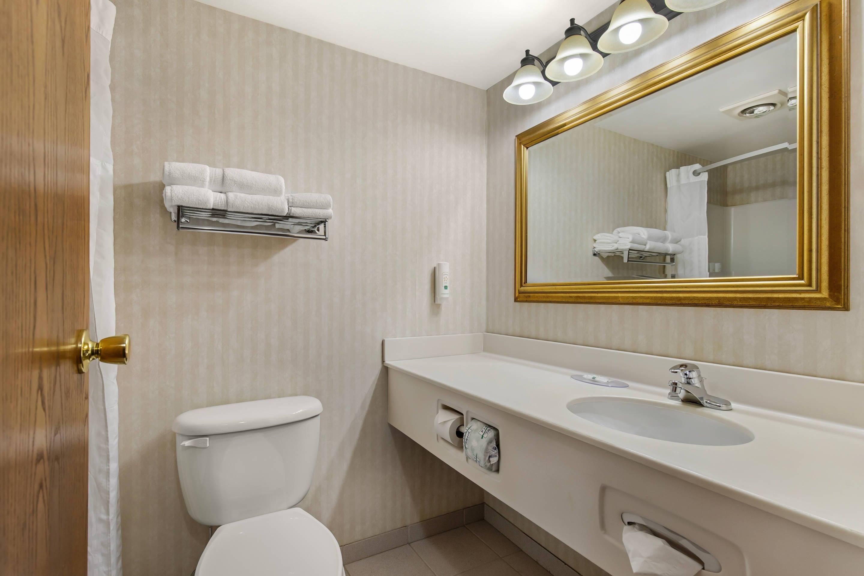 A bathroom with a white toilet, a sink with a mirror, and a towel rack.