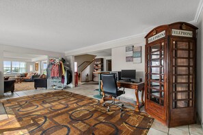 A spacious living area with a large rug, a telephone booth, and a dining area with a table and chairs. - Quality Inn & Suites Manistique (Manistique)