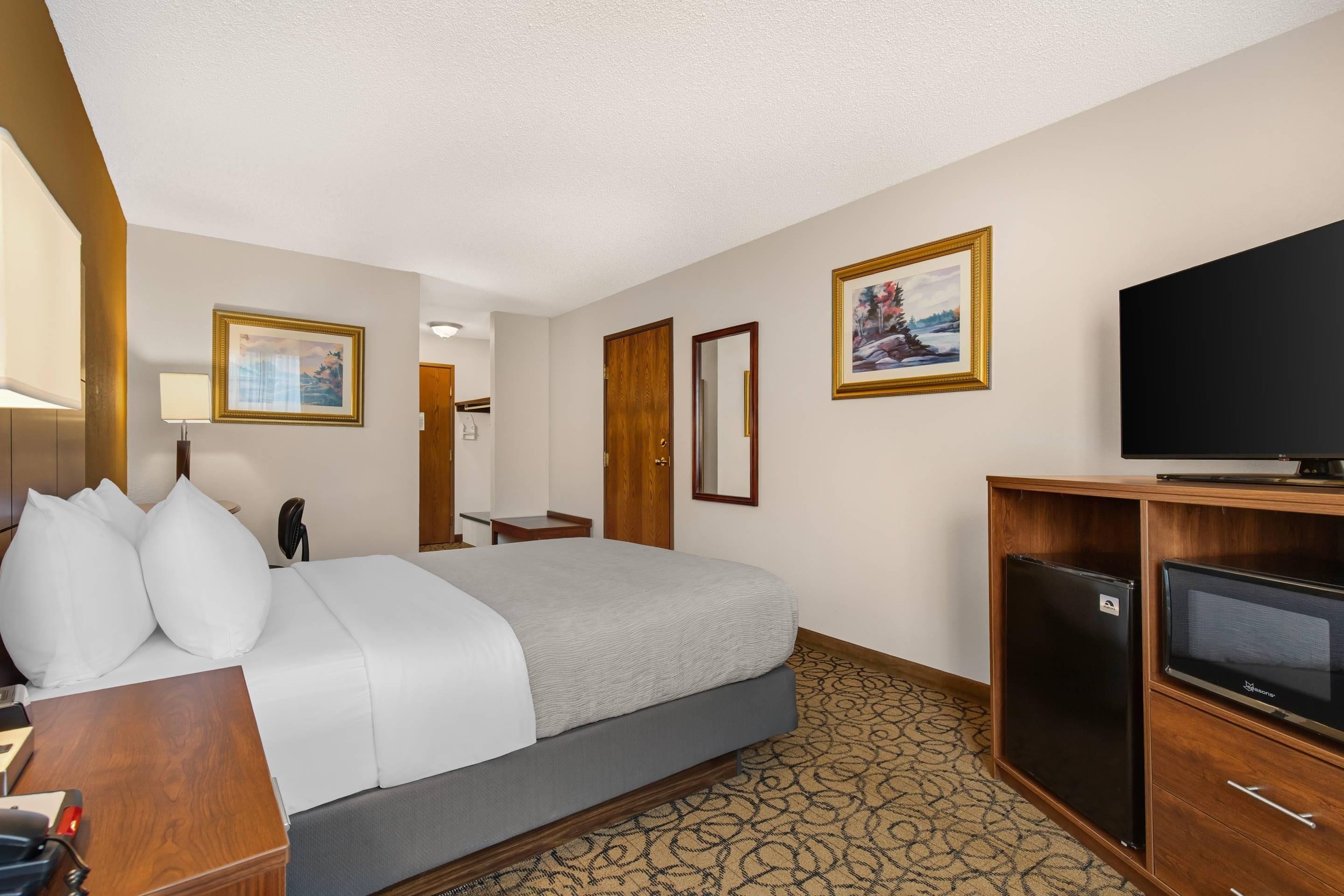 Une chambre d’hôtel équipée d’un lit, d’un bureau, d’une télévision et d’un réfrigérateur.