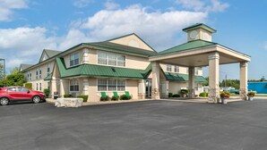 A hotel with a green roof, a covered entrance, and a parking lot. - Quality Inn & Suites Manistique (Manistique)