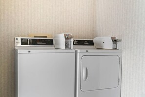 Two white washing machines stacked on top of each other against a textured wall. - Quality Inn & Suites Manistique (Manistique)