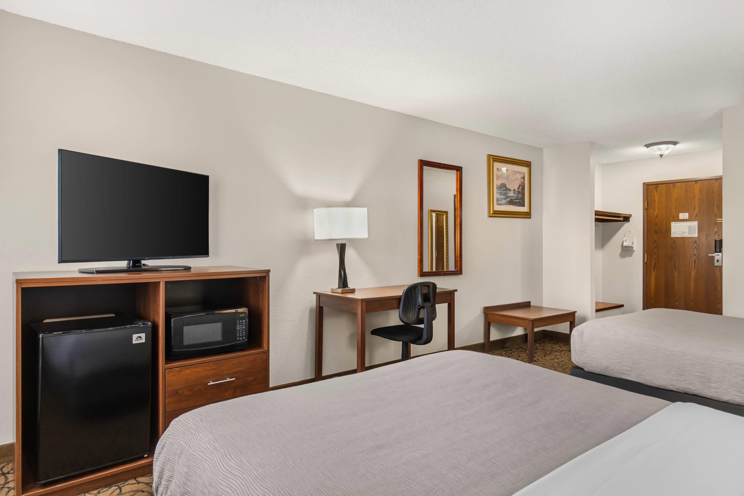 Une chambre d’hôtel équipée d’une télévision, d’un bureau avec une chaise, d’un lit et d’une porte.