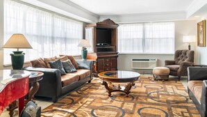 A living room with a sofa, armchair, coffee table, and a television set. - Quality Inn & Suites Manistique (Manistique)